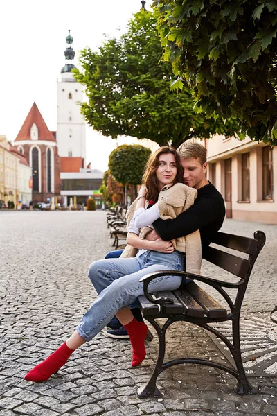 Hermosa pareja joven abrazándose en un banco en una ciudad europea. Cita romántica y concepto de amor. — Foto de Stock