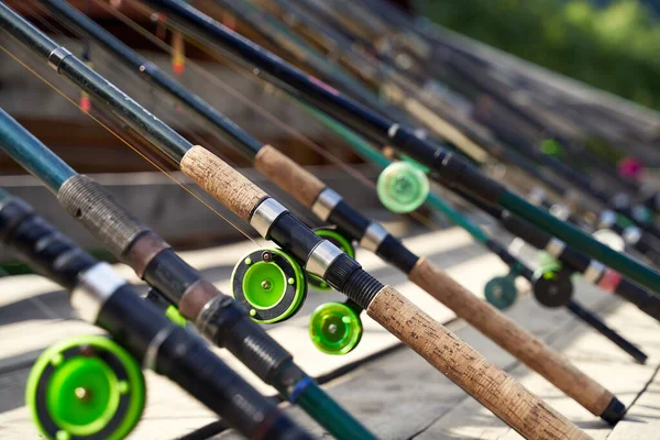 Molte canne da pesca sul molo di legno vicino al fiume o al lago in una giornata di sole — Foto Stock