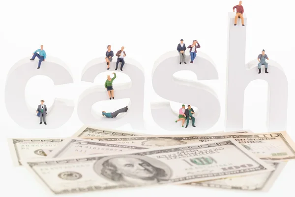 Miniature people sitting on cash letters — Stock Photo, Image