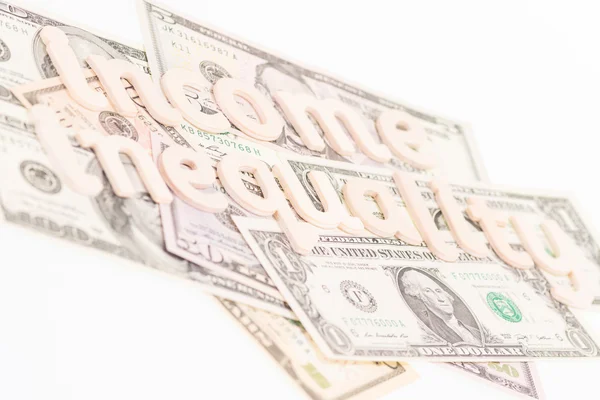 Income inequality wooden letters on banknotes — Stock Photo, Image