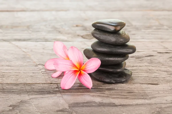 Fkiwers de plumeria e pedras pretas na madeira weathered — Fotografia de Stock