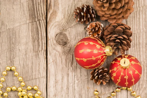 Rote Weihnachtskugeln, goldene Perlen und Tannenzapfen — Stockfoto