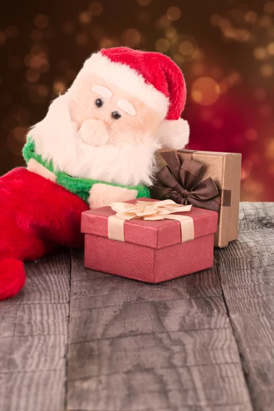 Santa Claus toy leaning against the gift boxes — Stock Photo, Image