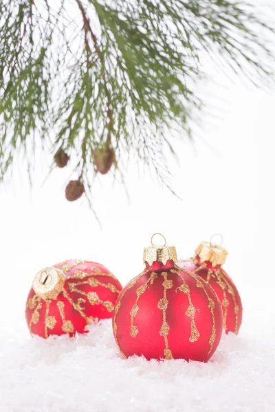 Rote Christbaumkugeln in Schneeflocken und Tannenzweig — Stockfoto