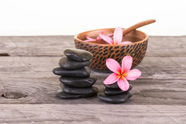 Plumeria flores y piedras negras sobre madera envejecida — Foto de Stock