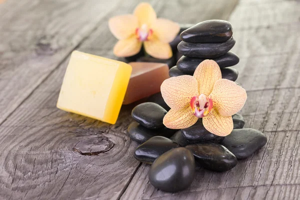 Phalaenopsis orchids, soaps and black stones on weathered wood — Stock Photo, Image