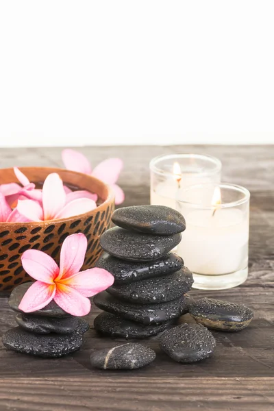Плюмерия цветы, черные камни и свечи на выветренной древесины крупным планом — стоковое фото