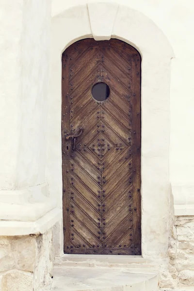 Puerta de madera vieja con pomo de metal y pequeña ventana redondeada —  Fotos de Stock