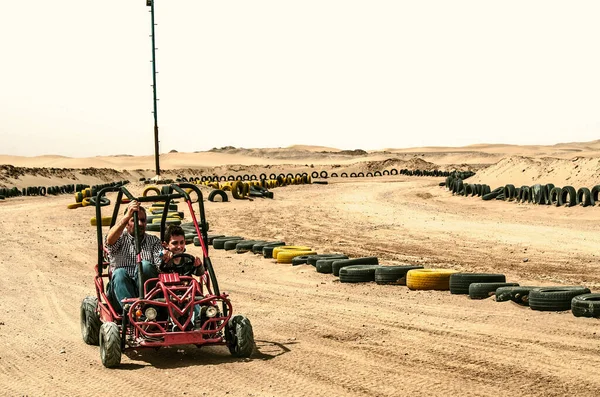 2021年2月20日 伊朗沙漠亚兹德 一个小男孩和他的父亲坐在一辆四轮驱动的自行车的轮子后面 骑着一条弯弯曲曲 崎岖的路 用黑色和黄色的汽车轮胎围住 穿过沙漠 — 图库照片