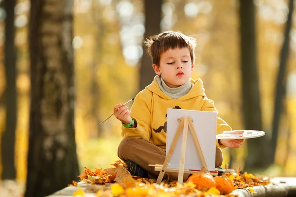 Söt liten pojke målning i gyllene höst park — Stockfoto