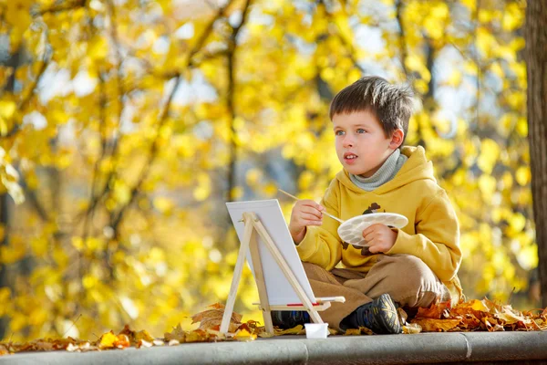 Bonito menino pintando no parque de outono dourado — Fotografia de Stock