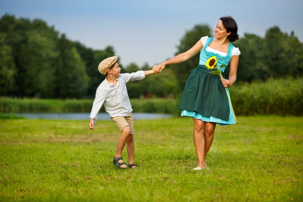 Jovem atraente em um dirndl com seu filho — Fotografia de Stock