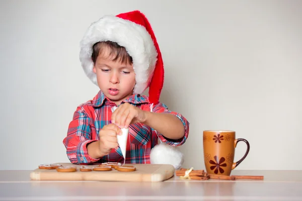 Cute little boy decorating the gingerbread cookies — ストック写真