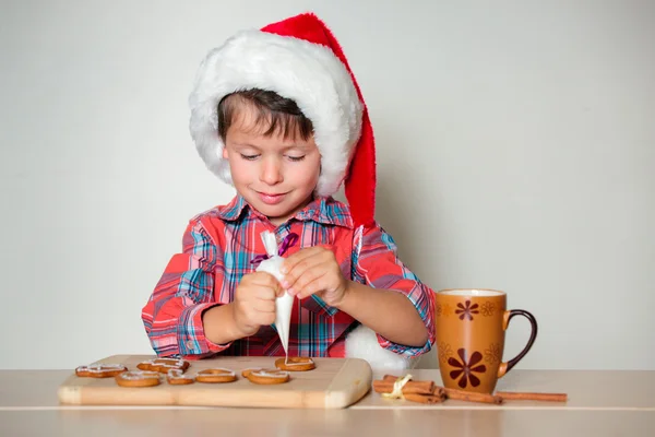 Liten pojke dekorera pepparkakor cookies — Stockfoto
