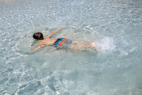 Kleine jongen in een ondiepe water zwemmen — Stockfoto