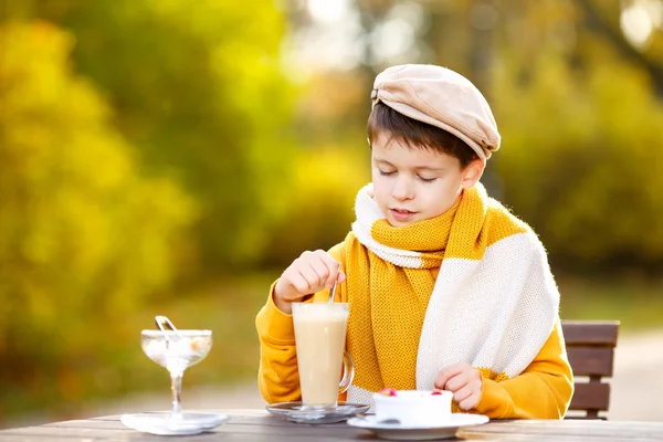 Liten pojke dricka varm choklad i café — Stockfoto