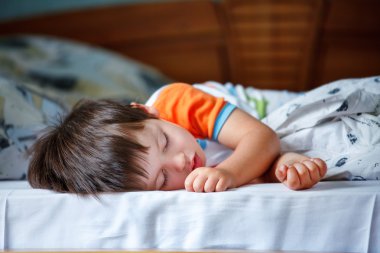 yatakta uyuyan sevimli küçük çocuk