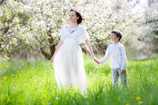 Glad kvinna och barn i blommande trädgård — Stockfoto