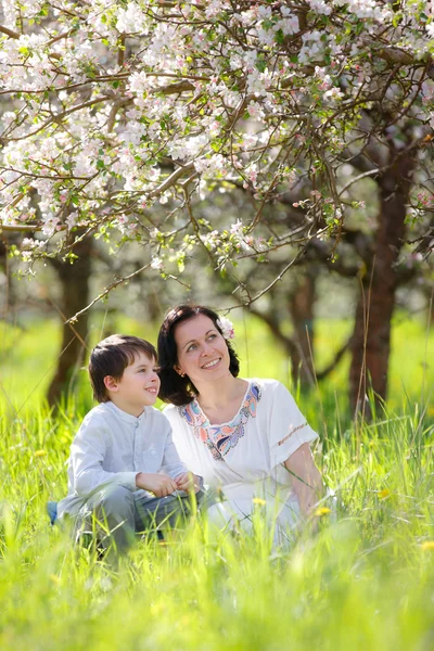 Glad kvinna och barn i vår apple trädgård — Stockfoto