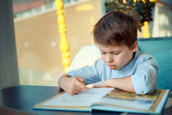 Langweiliger und müder kleiner Junge liest Buch — Stockfoto