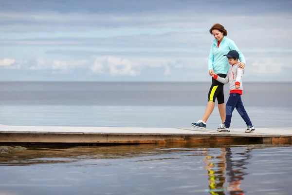 Mutter und kleiner Sohn gehen gemeinsam auf Holzsteg — Stockfoto