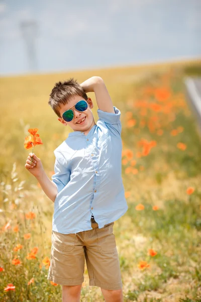 ケシの花の花束を屋外開催かわいい笑みを浮かべて少年 — ストック写真