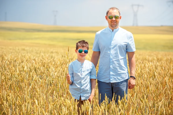 Glücklicher Vater mit kleinem Sohn, der glücklich im Weizenfeld spaziert — Stockfoto