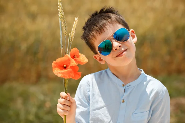 Bonito menino sorridente segurando buquê de papoilas ao ar livre — Fotografia de Stock