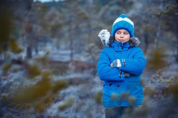 Rapaz bonito com coruja brinquedo no ombro na floresta de inverno — Fotografia de Stock