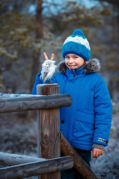 Schattige jongen met uil speelgoed op schouder in winter forest — Stockfoto