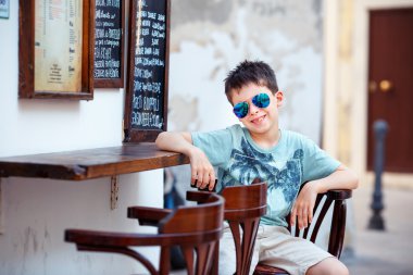 Açık kafe bir sandalyede oturan sevimli küçük çocuk