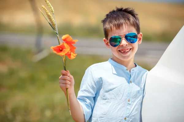 Lindo niño sonriente sosteniendo ramo de amapolas al aire libre — Foto de Stock