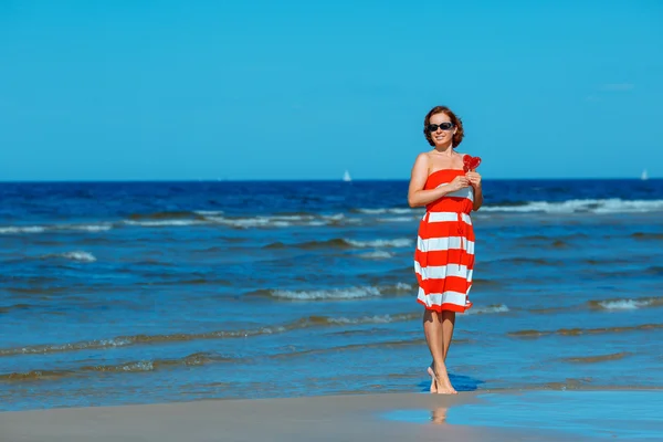 Junge schöne Frau hält Bonbonherz und genießt den Sommerurlaub am Strand — Stockfoto