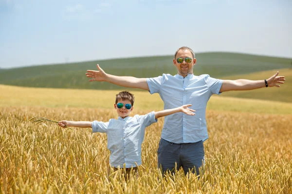Glücklicher Vater mit kleinem Sohn, der glücklich im Weizenfeld spaziert — Stockfoto