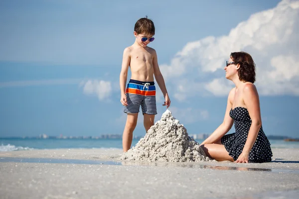 Joven madre y su pequeño hijo construyendo castillo de arena en la playa en Florida — Foto de Stock