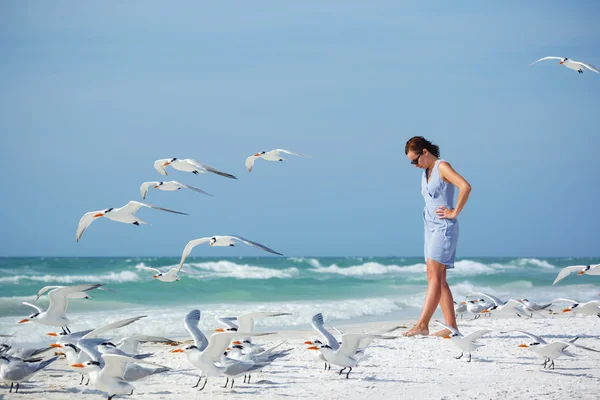 Jonge vrouw op een strand waar meeuwen vliegen — Stockfoto