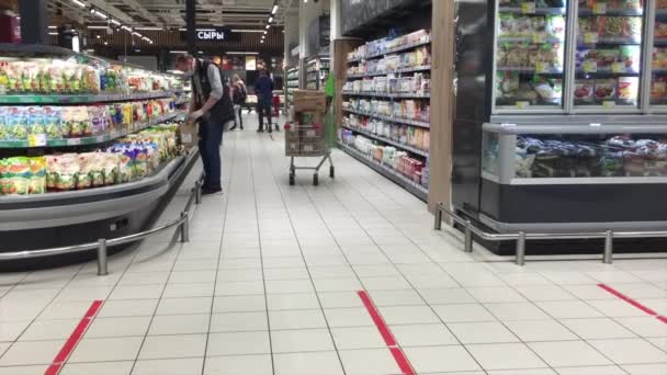 El vendedor que usa mascarilla facial y guantes pone productos lácteos en el mostrador del supermercado. Pasillos en una tienda de comestibles. Moscú — Vídeo de stock