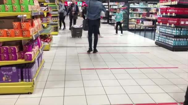 Люди в масках, які рухаються з шопінговими візками в проходах супермаркету. Окі гіпермаркет, Москва. Одяг на масках.. — стокове відео