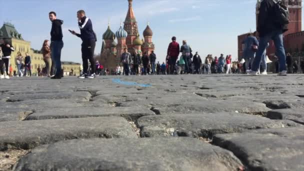 Pessoas caminhando na Praça Vermelha pavimentadas com pedra Gabbro-Diabase da República da Carélia. É uma pedra muito densa, resistente a impactos naturais e mecânicos. — Vídeo de Stock