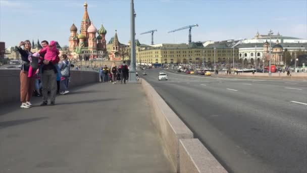 Moskou: Mensen die over de Bolsjoi Moskvoretsky brug lopen en foto 's van zichzelf maken met St. Basilius Kathedraal op de achtergrond. — Stockvideo