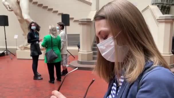 Excursions au Musée Pouchkine pendant la pandémie de coronavirus. Un jeune guide portant un masque facial répond aux questions du public. Visite du musée de Moscou. — Video