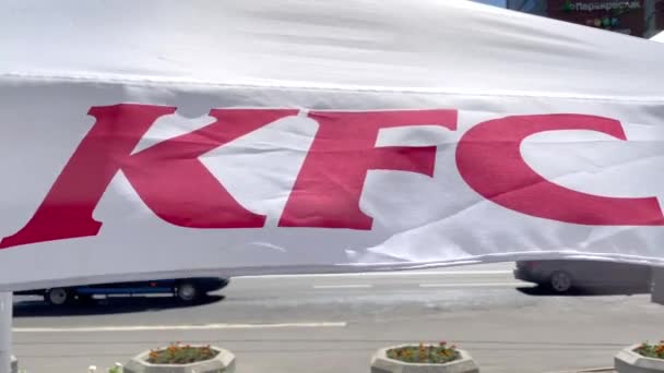 Detailní deštník značky KFC se chvěje ve větru. Letní terasa restaurace KFC fast food. Deštníková látka se vlní ve větru. 4K video 3840x2160 — Stock video