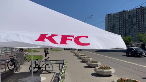 Moscou, Russie : Parapluie de marque KFC tremblant dans le vent. Pas encore prêt à être ouvert terrasse d'été vide du restaurant de restauration rapide KFC. Tissu agitant dans le vent. Restauration. Vidéo 4K 3840x2160 — Video