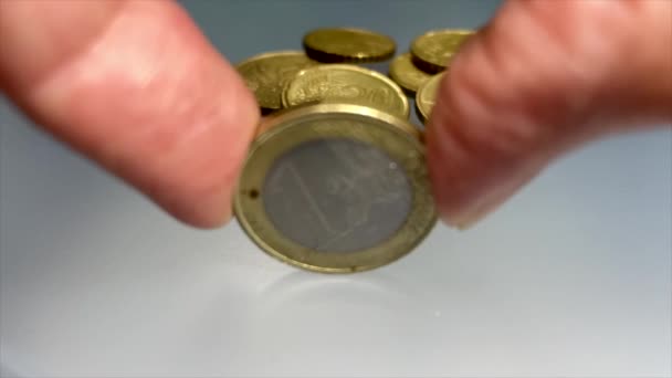 Mão feminina girando uma moeda de metal euro. Uma moeda de euro girando em câmera lenta em uma superfície de vidro fosco azul. Moeda da UE. Fundo da União Europeia. Moeda giratória. Sistema monetário europeu. Cinquenta e cinco — Vídeo de Stock