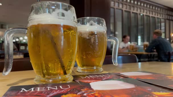 Restoran menüsü ve Çek restoranındaki ahşap masada iki bardak soğuk bira. — Stok video