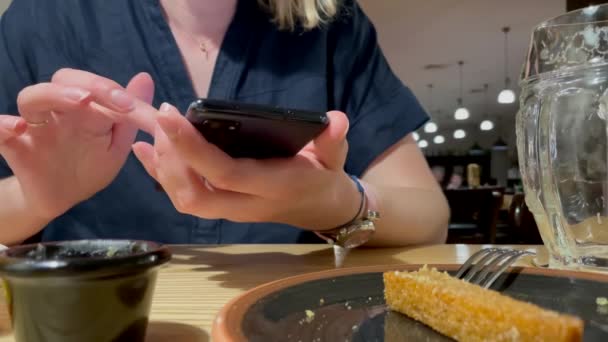 Jeune femme défilant et touchant écran de téléphone mobile. Smartphone utilisant au restaurant. Téléphone à défilement manuel, défilement mobile. — Video