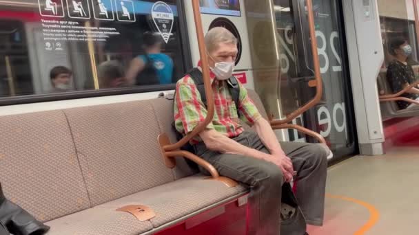 Moskou, Rusland - 07.09.2021: Oudere man met gezichtsmasker slaapt in een metro. Mensen in Moskou metro. Moderne goed uitgeruste ondergrondse trein Moskou. Moe van een man. Metropassagier. — Stockvideo