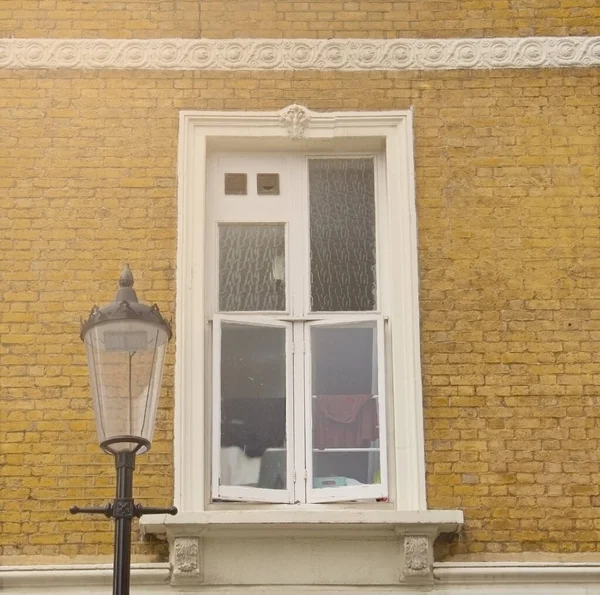 Window of traditional British Georgian houses in London. Facade of a yellow brick residential house. Clothes are drying on the window. Brick wall. Architectural background.