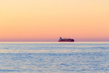 Uluslararası Konteyner Kargo gemisi gün batımında açık deniz ufkunda. Uluslararası su taşımacılığı. Yan görüş. Bulanık hareket halinde odaklanmış bir fotoğraf. Batumi, Georgia