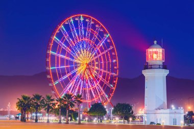 Akşam vakti lunaparkta dönme dolap. Batumi Bulvarı. Fotoğraf uzun süre çekilir ve hareket bulanıklığı vardır.. 